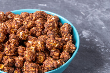 Chocolate popcorn in a blue cup on a dark background.