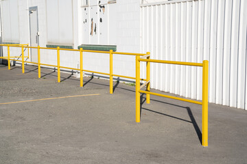 Fototapeta premium Yellow fences for walkway close to white wall of factory.