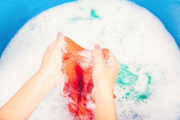 Fototapeta premium Closeup young Asian woman use hands washing color clothes in basin with detergent have soapy bubble water, studio shot background, laundry concept