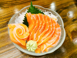 sashimi, japanese food, slice salmon served in glass bowl on wood table.