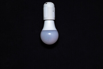 LED lamp hanging on a black background. Electricity Saving Concept. The photo