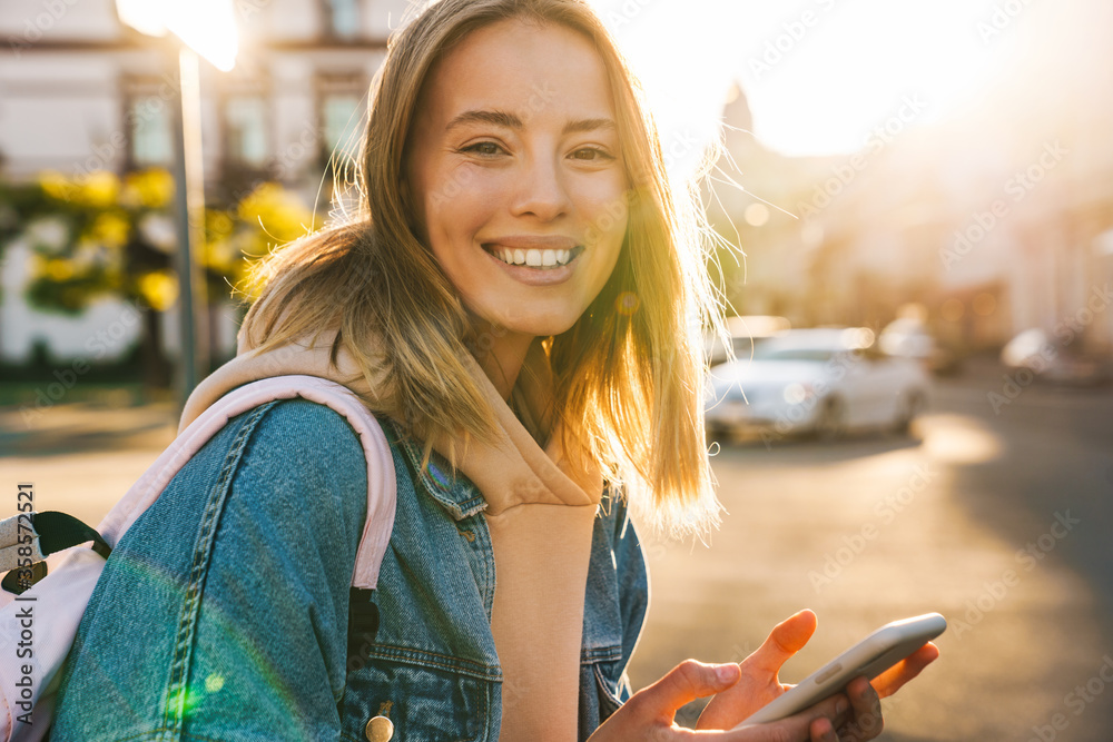 Poster Cheerful young blonde girl using mobile phone