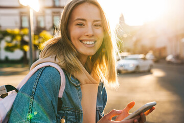 Cheerful young blonde girl using mobile phone