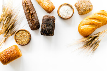 Different kinds of fresh bread on kitchen table top view space for text