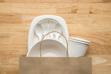 Natural eco-friendly disposable utensils (fork, spoon, dish plate, bowl, cup) in recycle paper bag...