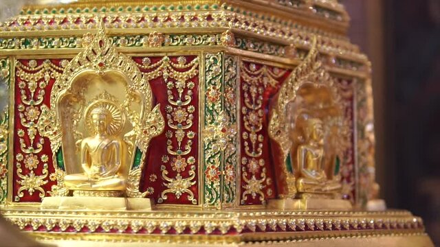 Dhatu or sarira are small that look like pearls or crystals formed after the body is cremated after the death of Buddhist monks. Small golden and shiny buddha statue.