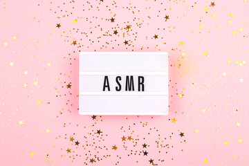 The lamp with letters ASMR on pink background. Decorated with confetti. Sound and visual practice for anxiety, stress and panic relief.  Flat-lay.