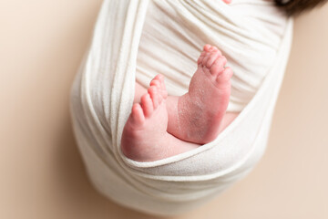 feet of a newborn baby. baby legs on beige background. little foot