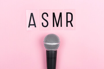 A microphone and letters ASMR on pink background. Minimal compostion.