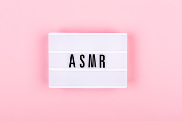 The lamp with letters ASMR on pink background. Sound and visual practice for anxiety, stress and panic relief.  Flat-lay.