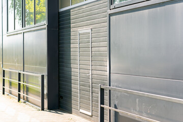 Details of gray facade with windows on industrial building reflect clouds on windows