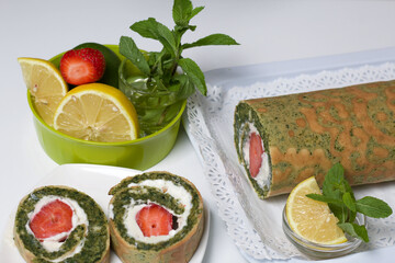Spinach and mint roll with strawberry filling. A roll cut is visible. Near lemons and mint.