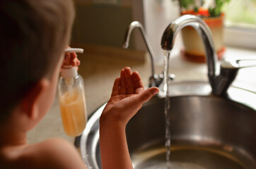 The child washes his hands in the house. Water tap for washing hands.