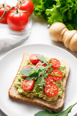 Avocado rye bread toast with cherry tomatoes and arugula.