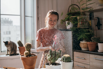 A young woman replants and water cacti at home