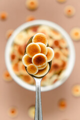 Little pancakes with strawberries in a plate. Cereal Pancakes in a bowl on a brown background.