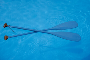 Two blue wooden paddles swim crossed in the water