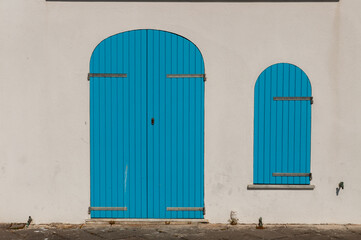 Blue door and window in white wall, typical house of Alghero, Sardinia