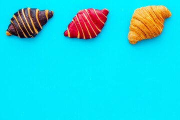 Set of croissants - chocolate, berry, classic - on blue table top view