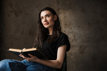 Photo of beautiful young woman sitting on chair and reading book