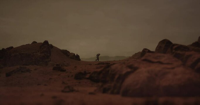 Lonely astronaut walking on a surface of a red rocky planet. Mars colonization concept. Dust effect added