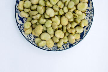 raw broad bean on a plate on white background, flat lay