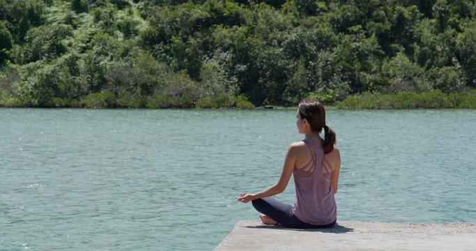 Woman do yoga and sit at lake side