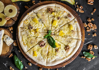 Cheese pizza with pear and nuts on a dark background