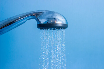 Naklejka na ściany i meble Shower water on a blue background. The flow of water from the shower. Shower in the bathroom