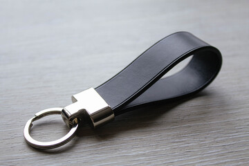 Black keychain (accessory) on a gray table made of genuine Italian leather handmade