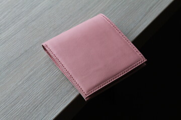 Handmade pink purse (wallet) made of genuine leather. Handmade Christmas tree stitch. Lying on a gray table side view