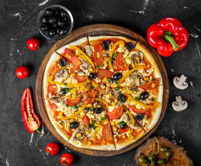 vegetarian pizza with paprika, olives, mushrooms, corn, tomato slices, cheese and green onions on a wooden board