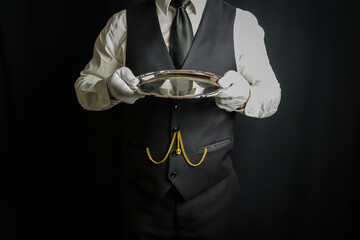 Butler in White Gloves and Waistcoat Dutifully Holding Silver Tray. Concept of Service Industry and Professional Hospitality. Dependable Servant. Copy Space for Service.