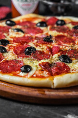 salami pizza with olives on a dark background