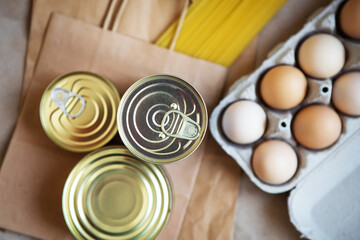Eggs, canned food, pasta, products in environmentally friendly craft packages. Vegetarian healthy organic foods from the market. Donation, help for those in need. View from above