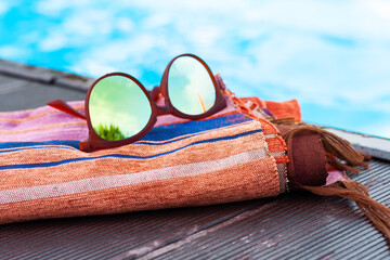 sun glasses, cover-up beachwear wrap near swimming pool, tropical background.