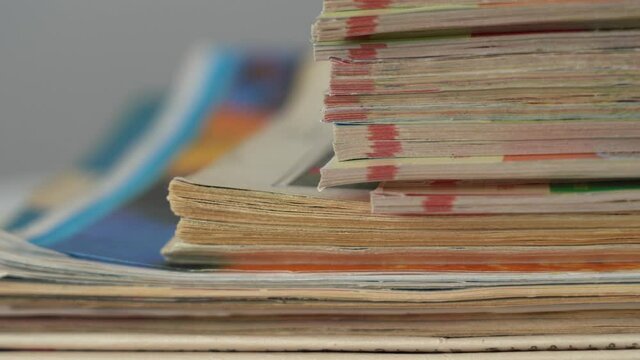 Closeup up view 4k video footage of stack of many old paper magazines isolated on table.