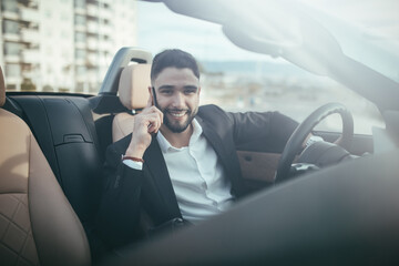 Front view of businessman talking on the phone inside a car