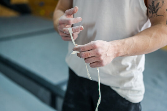 From above of anonymous male athlete in active wear standing and taping fingers in talcum powder in gym