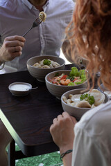 Couple eating lunch, breakfast or brunch outside the cafe, salad, tea, wrap, waffles, pouched eggs and dumplings