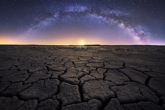Majestic scenery of drought cracked lifeless ground under colorful Milky on background