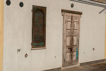 Rural closed door and window in white wall, typical house of Alghero, Sardinia