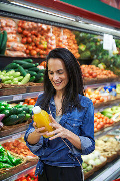 Brunette woman in a fruit shop confiding a fruit and vegetable smoothie