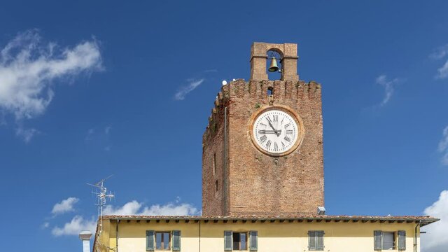 The ancient clock tower in the historic center of Cascina, Pisa, Italy, against a beautiful blue sky with white clouds in time lapse motion
