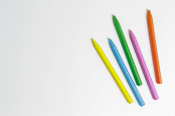 Bunch of different colorful wax crayon pencils laid oun in composition, isolated on white. Soft pastel for drawing. Close up, copy space, top view, flat lay.
