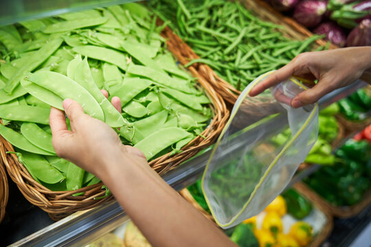 Female Hand Picking Up Beans From A Basket With Reusable Bag