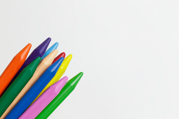Bunch of different colorful wax crayon pencils laid oun in composition, isolated on white. Soft pastel for drawing in stack. Close up, copy space, top view.