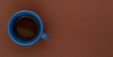 Top view, flat lay of black coffee cup on background brown.