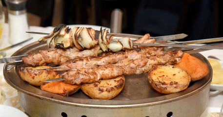 skewers on skewers with fried potatoes, sweet potatoes and onions