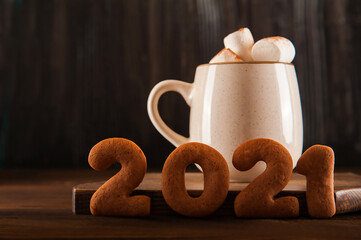 Concept with marshmallows in a mug and gingerbread cookie on a dark background. Christmas, coffee, tea, mug, marshmallows, cozy. Happy new year 2021. Winter concept close-up and copy space on dark bac